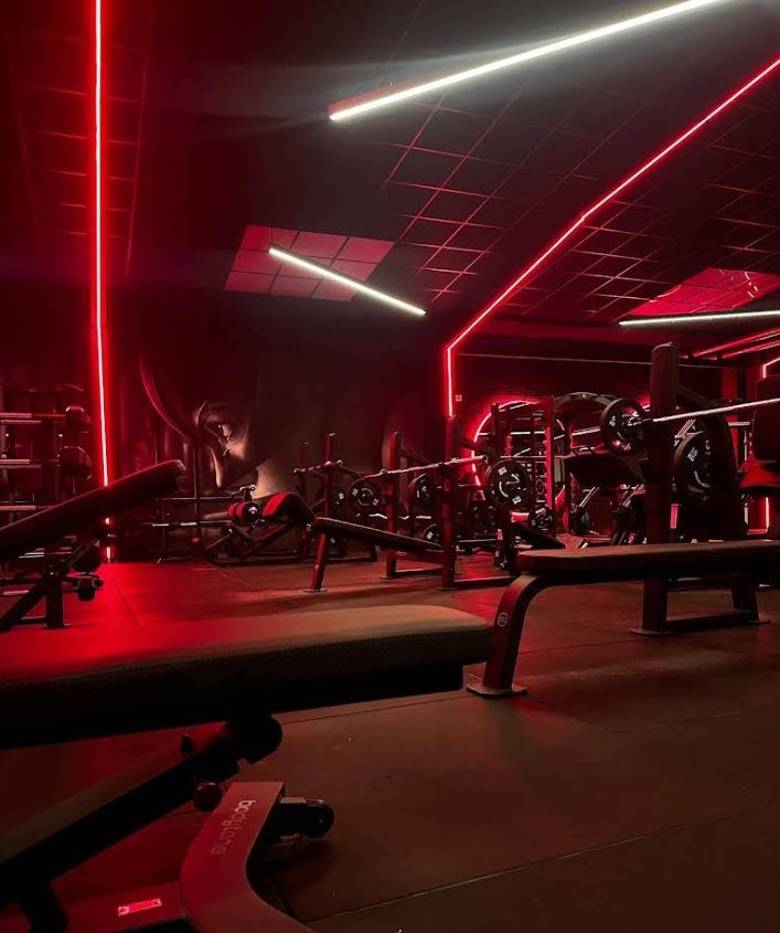 Sala de gimnasio de Vulture con neón azul y máquinas de fuerza
