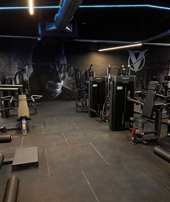 Zona de máquinas de musculación de Vulture bajo neón magenta