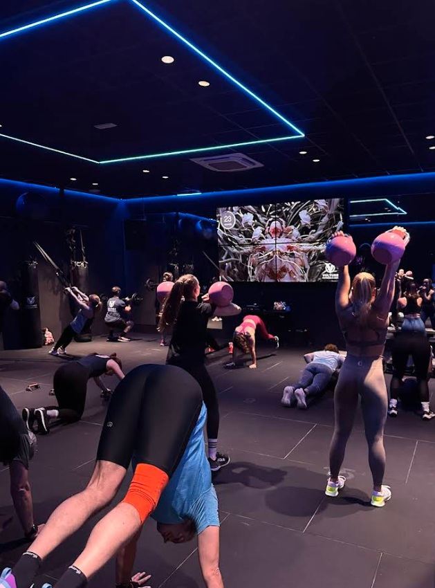 Clase colectiva dirigida con kettlebells y neón azul en Vulture
