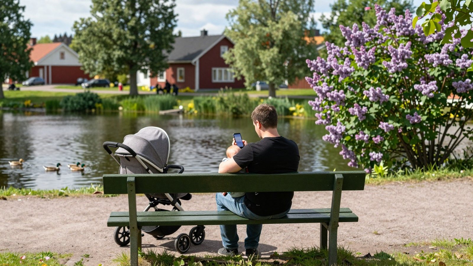 Isä istuu puiston penkillä nukkuva vauva sylissään ja pitelee puhelinta toisessa kädessä